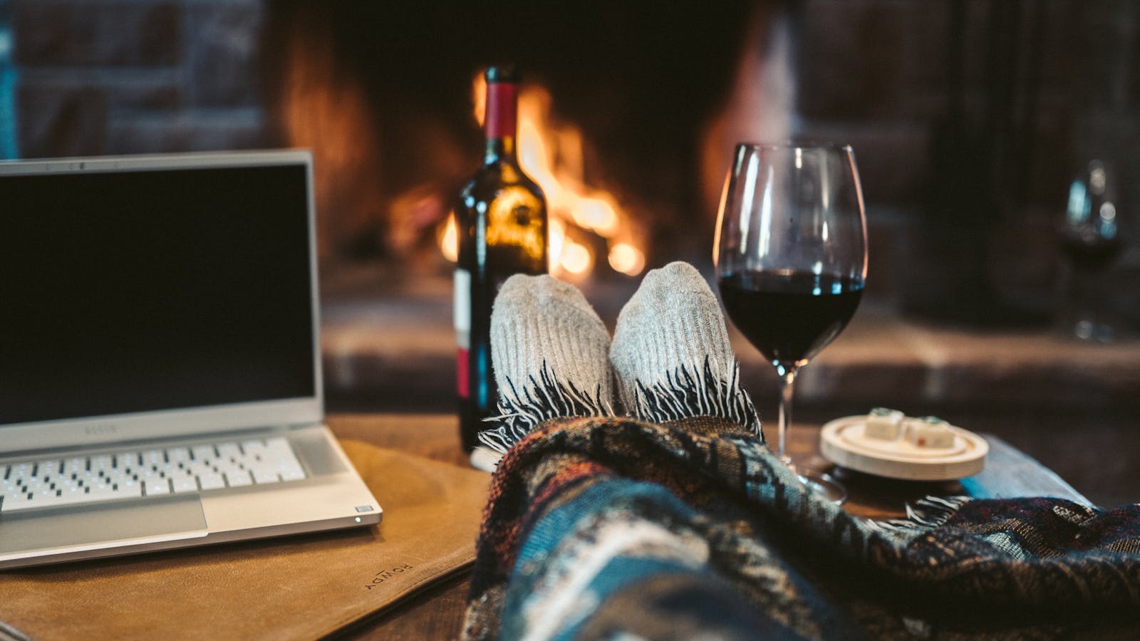 Macbook Pro Beside Wine Glass on Brown Wooden Table