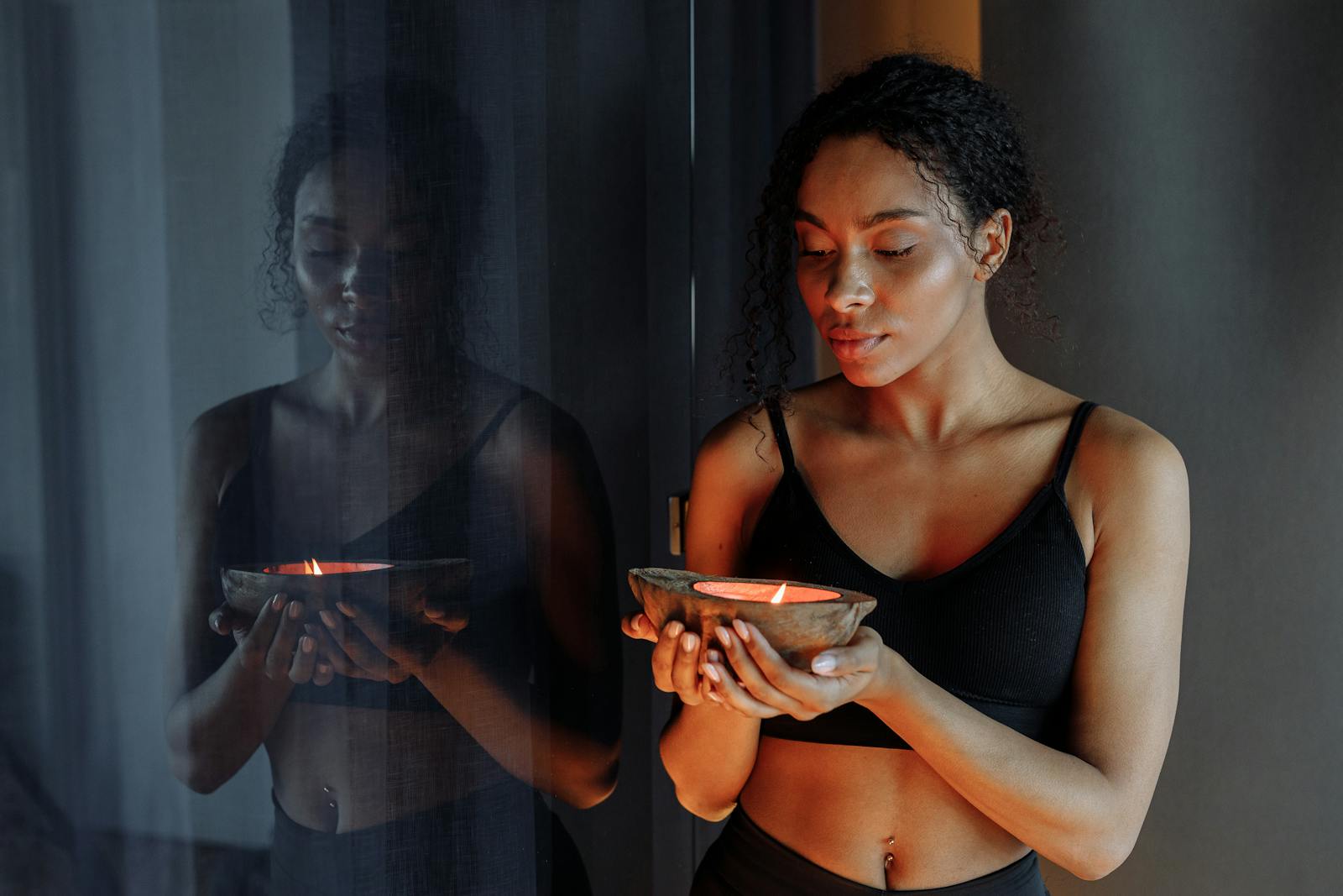 Photo of a Woman with Curly Hair Holding a Lit Candle